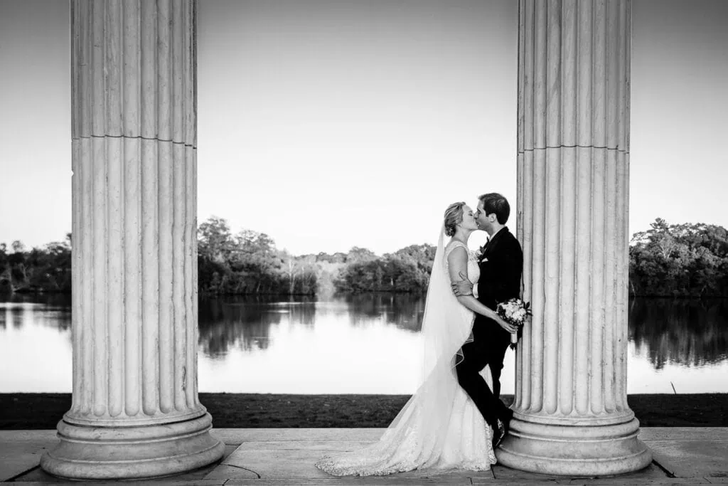 A bride and groom kiss and lean up against one of the columns at the temple to music at roger williams park