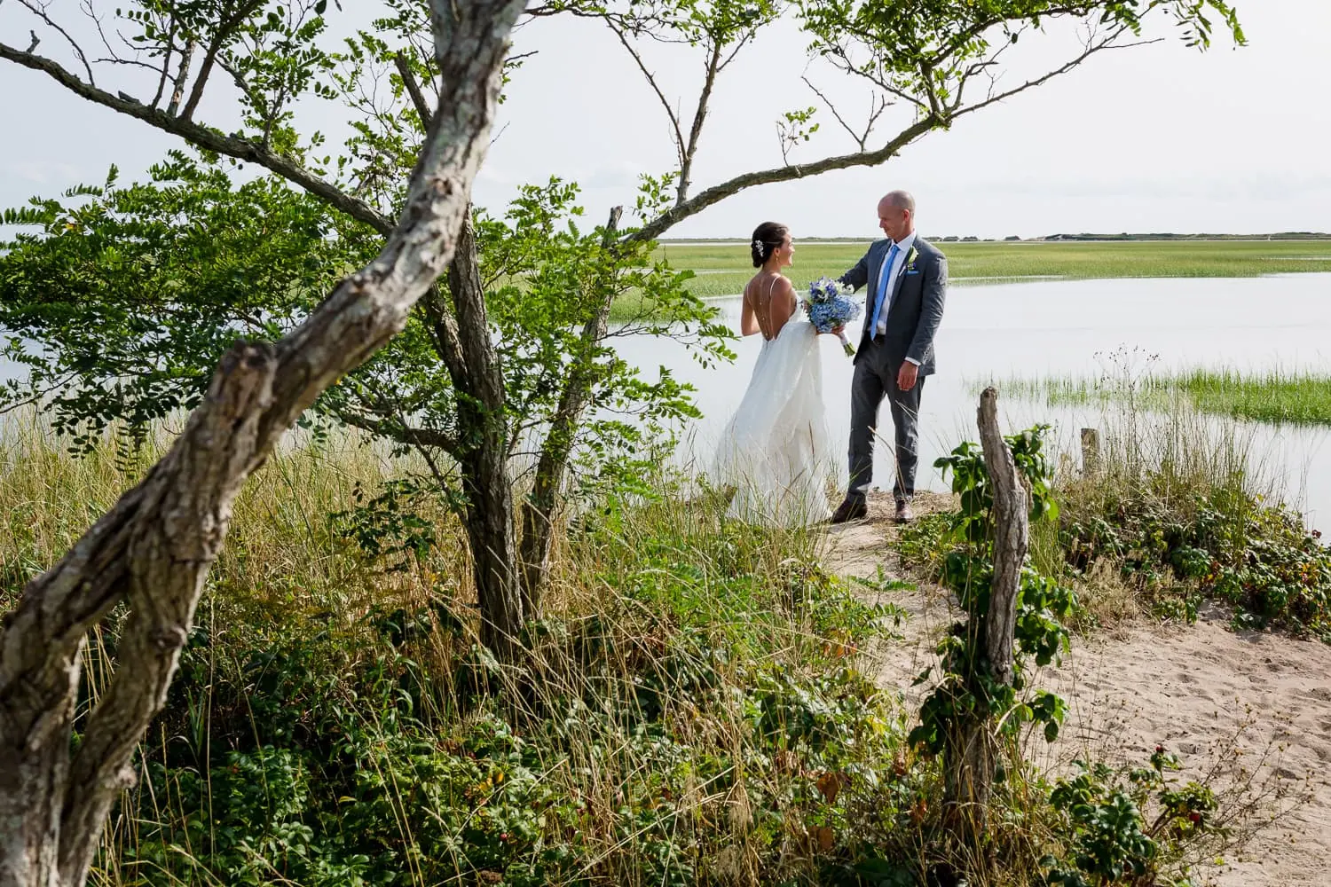 A bride and groom dancing by the edge of a marsh
