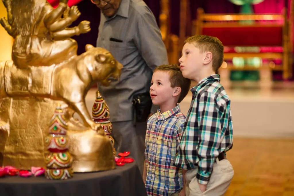 Two boys look at an indian wedding statue