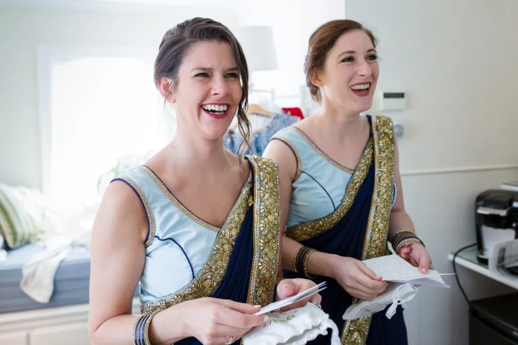 Two women in light blue saris react to opening wedding party gifts