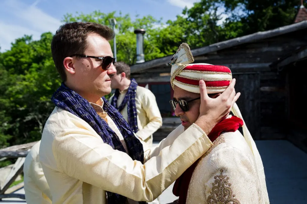 A man helps the groom adjust his turban