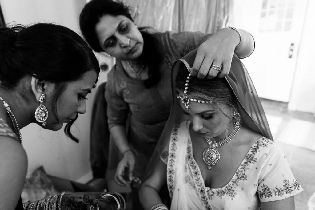 women help a bride adjust her headpiece