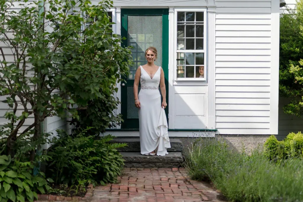 A bride walks out of a house with green door and white siding