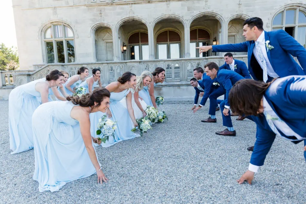 A row of bridesmaids lines up in football formation against a row of groomsmen