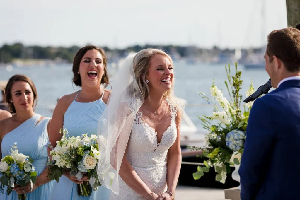 A bride and her maid of honor laughing during the wedding ceremony