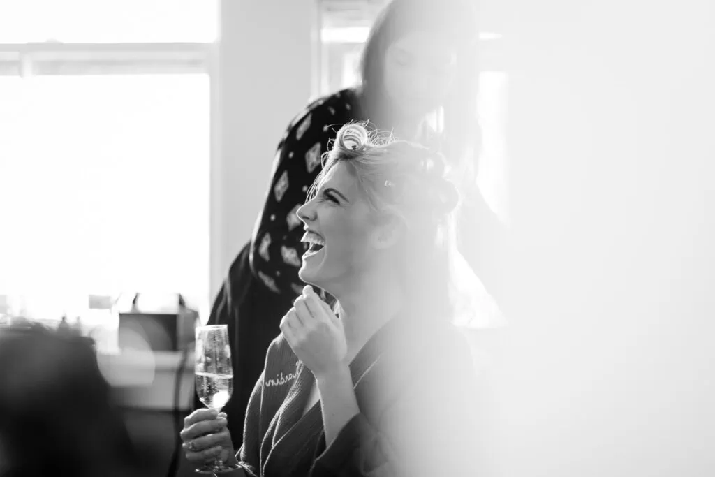 A woman laughing holding a glass of champagne