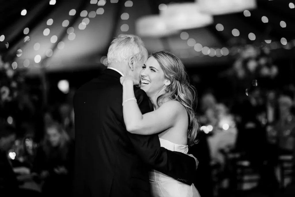 A woman laughing as she dances with an older man