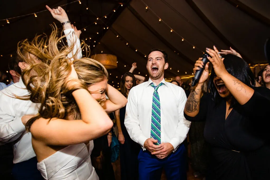 A man yelling on a dance floor with a woman swinging her hair back