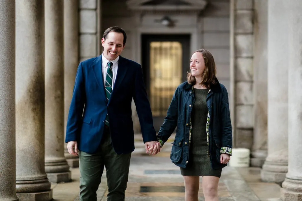 A couple wearing navy and green walk through the providence superior court for their engagement photos