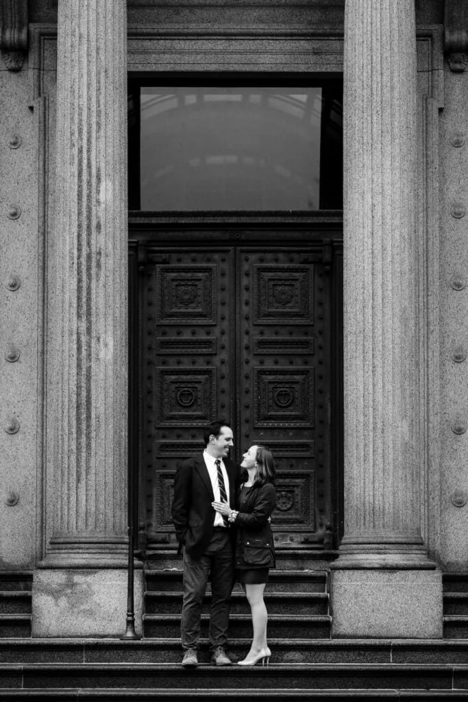 A couple on the steps of the old stone bank in providence for their engagement photos