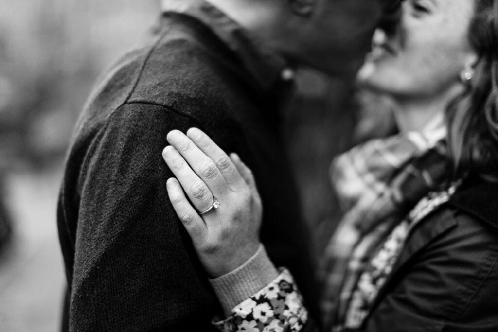 A black and white photo of a woman and man kissing with her engagement ring on her finger