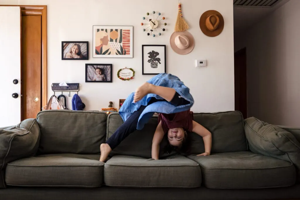 A photo of a little girl doing a cartwheel on a green couch during a day in the life photo session