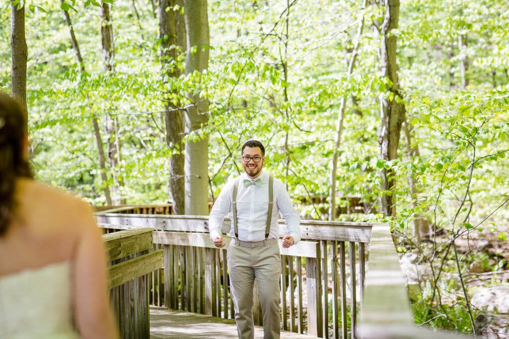 A groom reacts to seeing his bride during a first look at stamford nature center