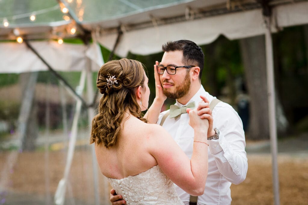 A bride adjusts grooms glasses during their wedding first dance