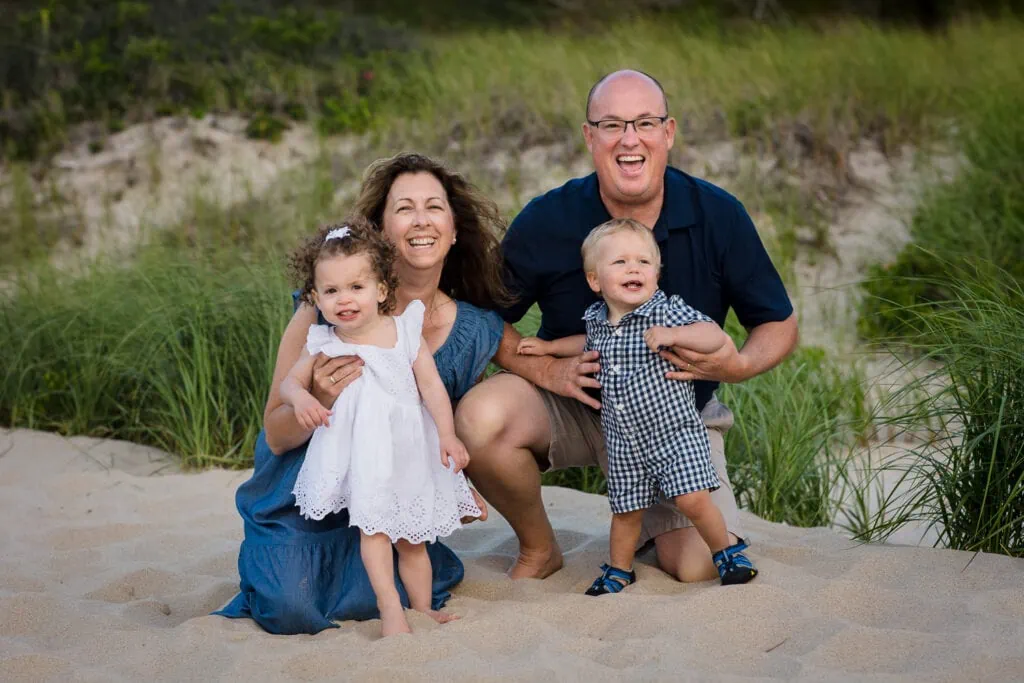 Two grandparents pose on the beach with their two grandchildren