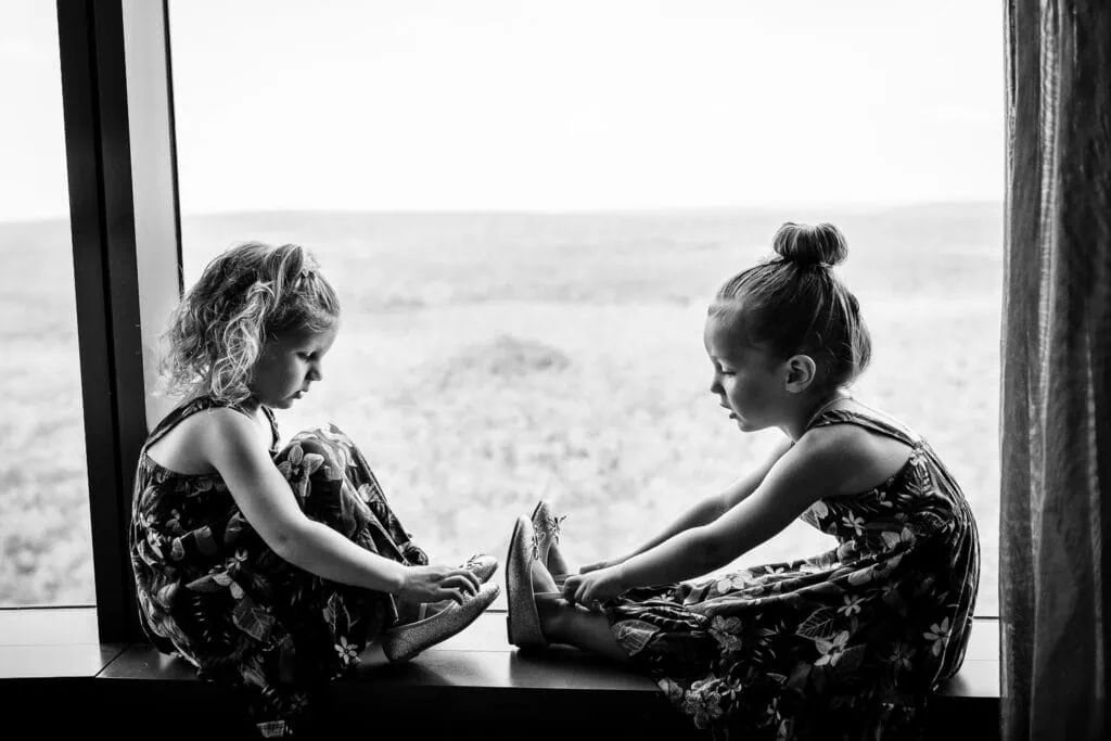 Two little girls sit on a windowsill