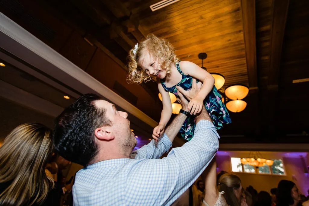 A man holds a little girl up in the air laughing