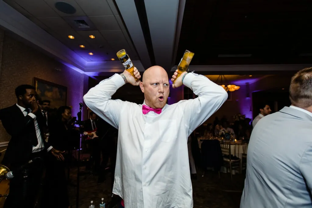 A man holds two two corona bottles over his head