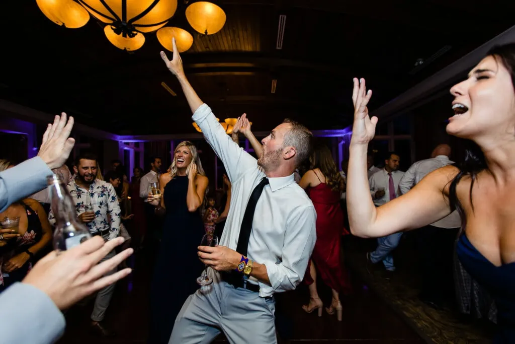 wedding guests dance with their arms raised in the air