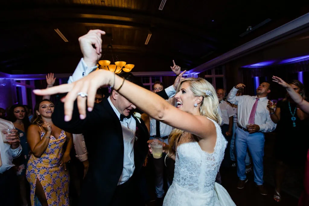 A bride and groom dance at their wedding with arms in the air