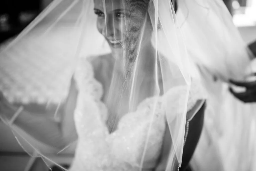 A woman smiling underneath her bridal veil