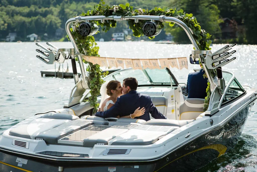 A bride and groom kiss in a boat that has a sign that reads "just married"