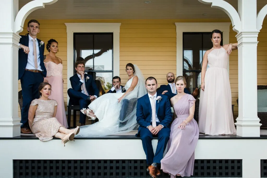 A bridal party sit on a porch with serious faces