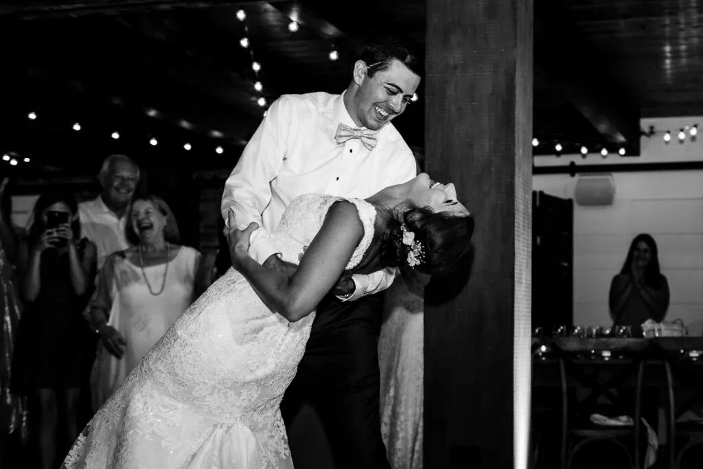 A groom dipping his bride while guests laugh in the background
