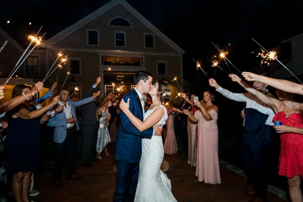 A bride and groom kissing inbetween rows of sparklers in front of the Pickering House