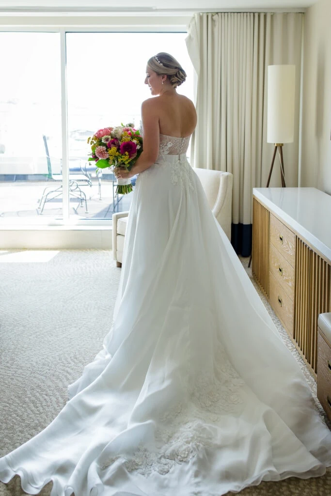 A bride with long dress train as seen from behind in a hotel room