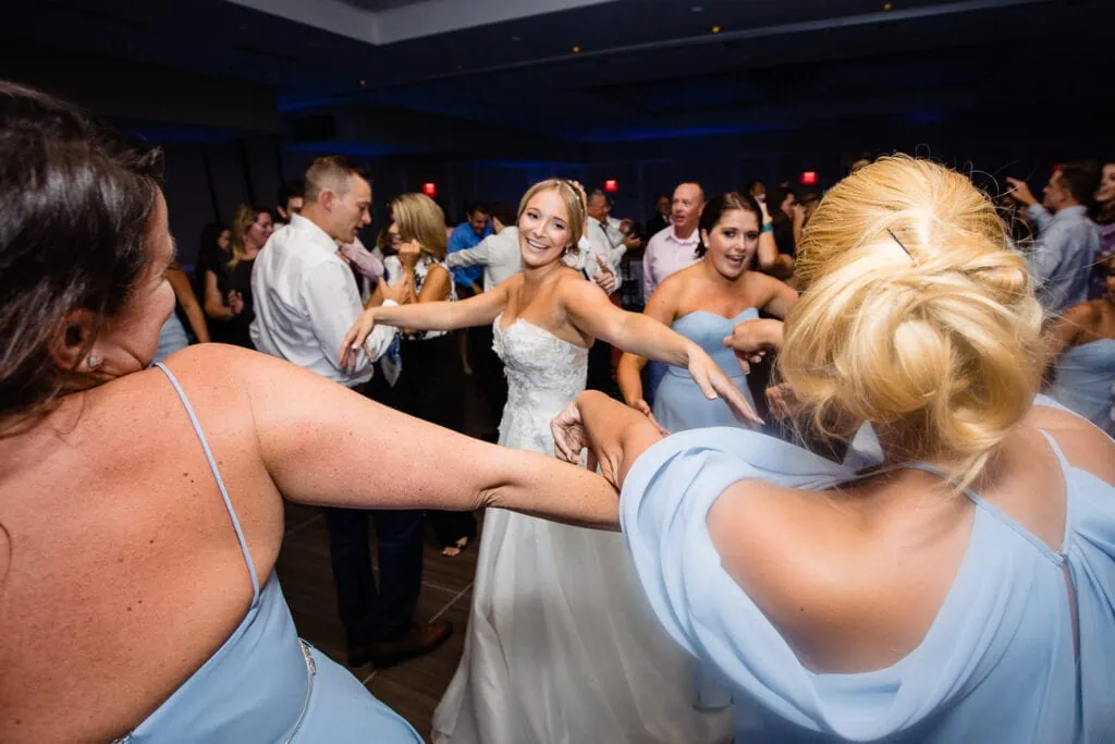 A bride dancing among other women on a dance floor
