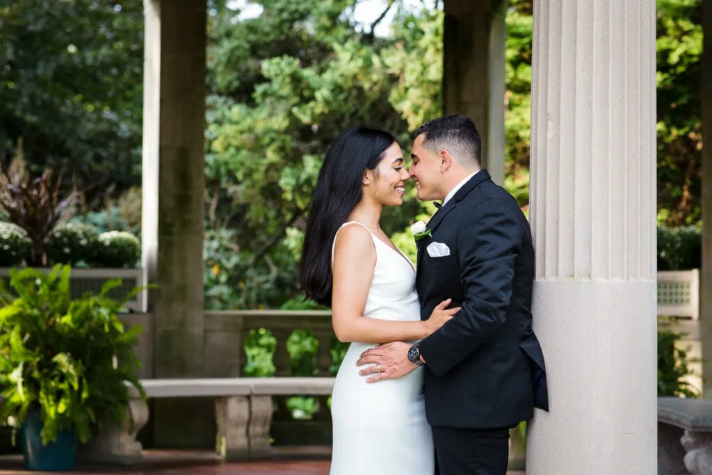 A bride and groom lean in for a kiss in the italian garden before their Eolia mansion wedding reception