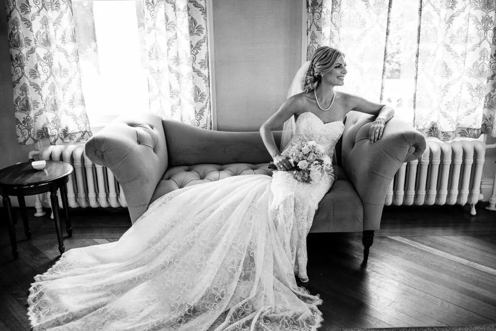A bride lounges on an antique chaise before her wedding in the Haley mansion at Inn at Mystic