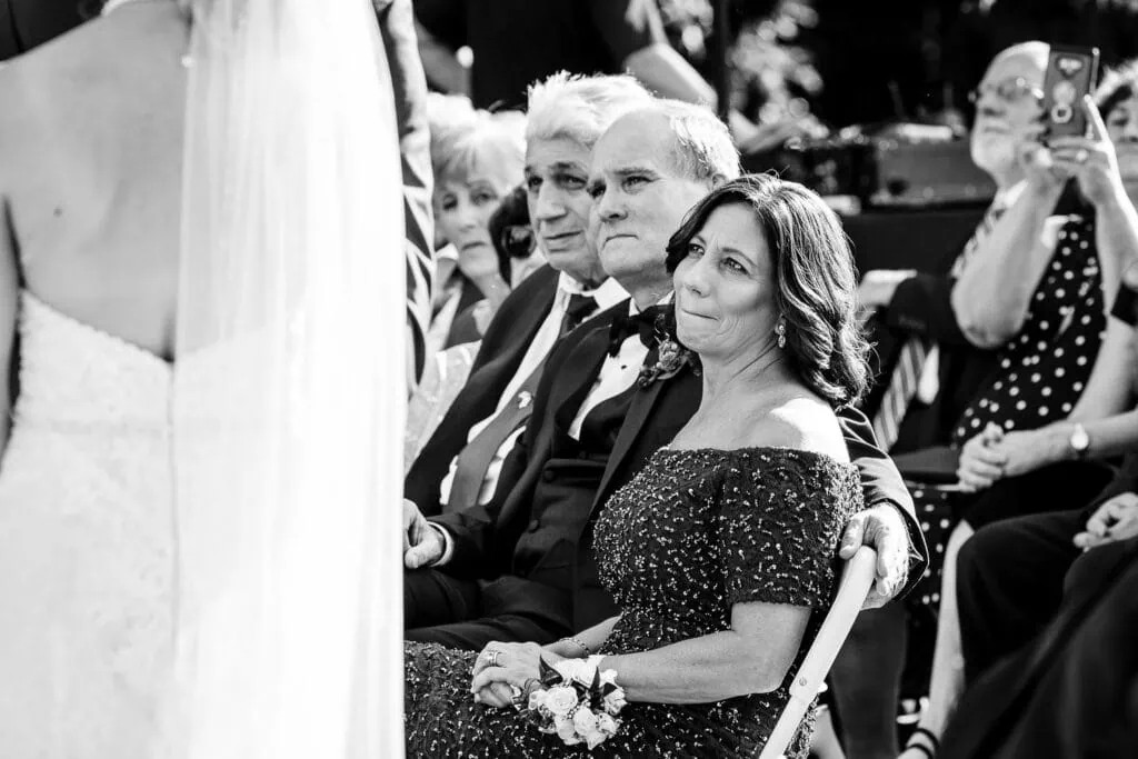 The mother of the groom holds back tears as she watches her sons wedding ceremony