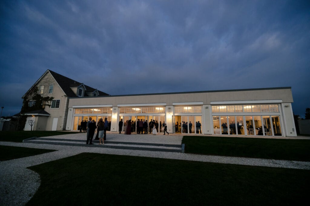 An exterior view of Belle Mer a rhode island wedding venue at dusk filled with wedding guests