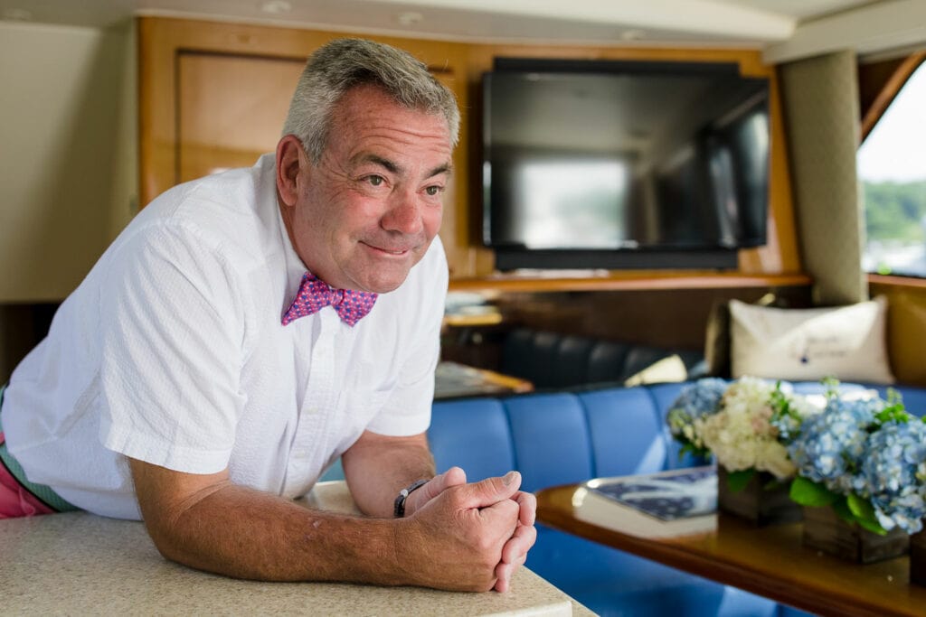 A groom in pink bowtie waits for his wedding to start in the cabin of his boat