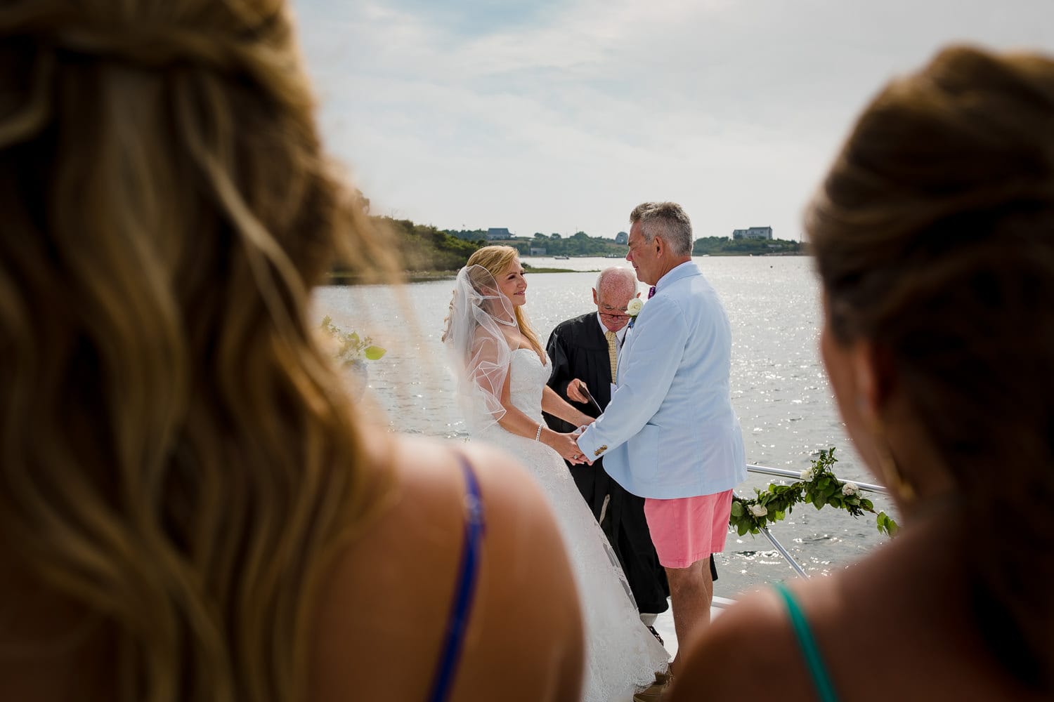 Two guests watch as the bride and groom get married on the bow of their boat during their block island wedding