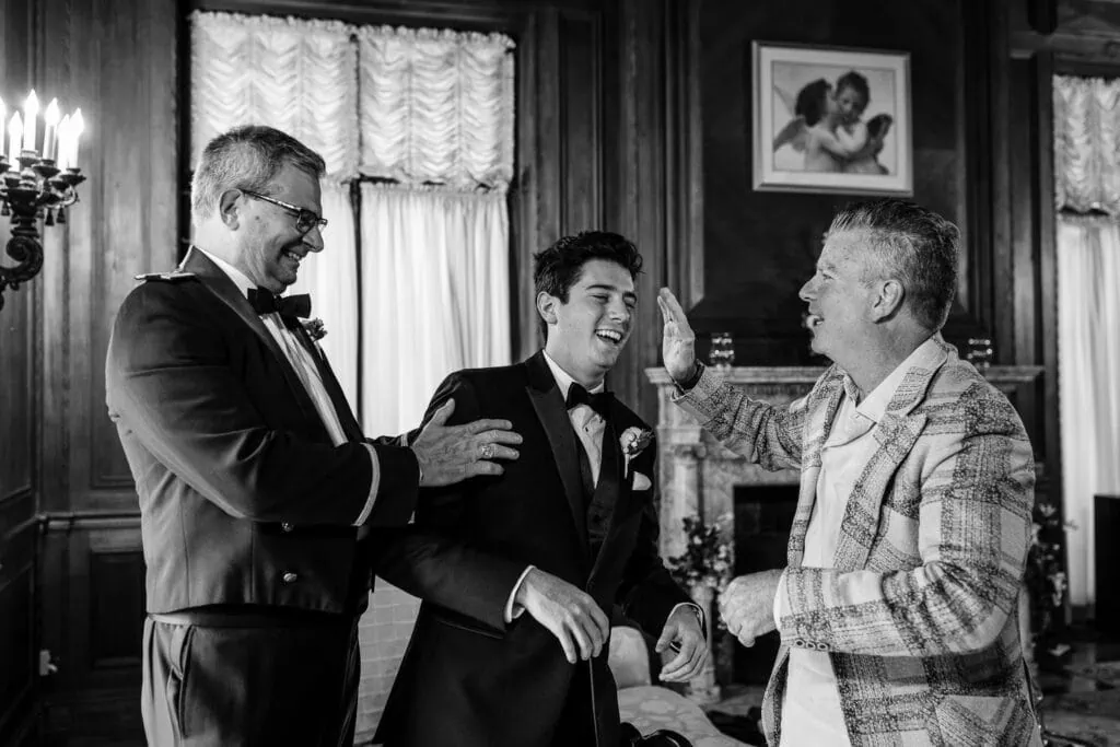 Men in suits joke around in an ornate room