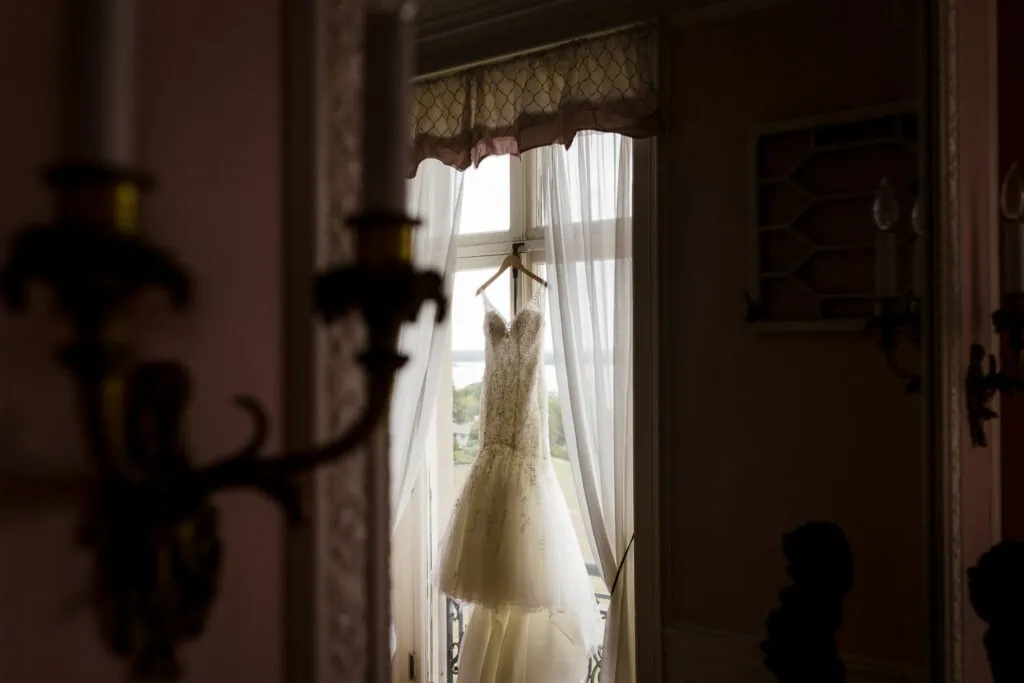 A wedding dress hangs in the window at aldrich mansion