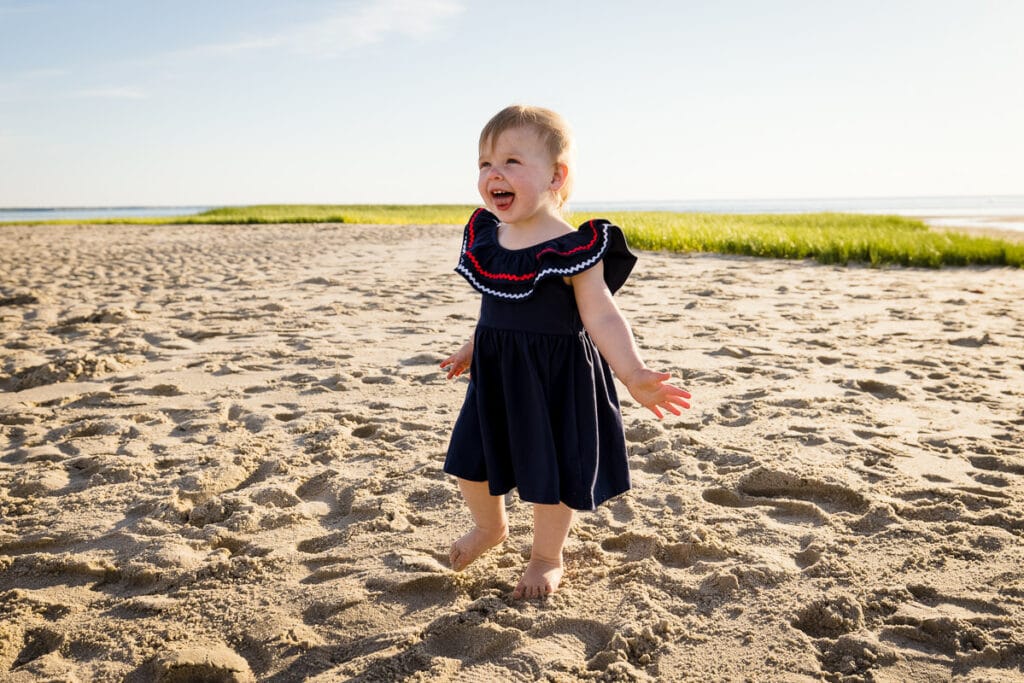 A toddler girl laughs on the beach