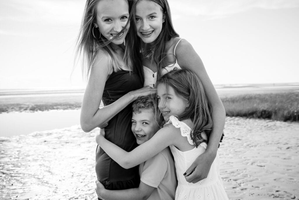 A black and white photo of two girls hugging their little cousins during an eastham family photo session