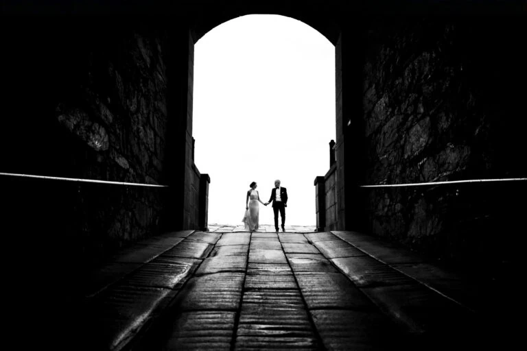 A couple walking hand in hand through a large stone tunnel at one of Rhode Island's oldest wedding venues - Fort Adams