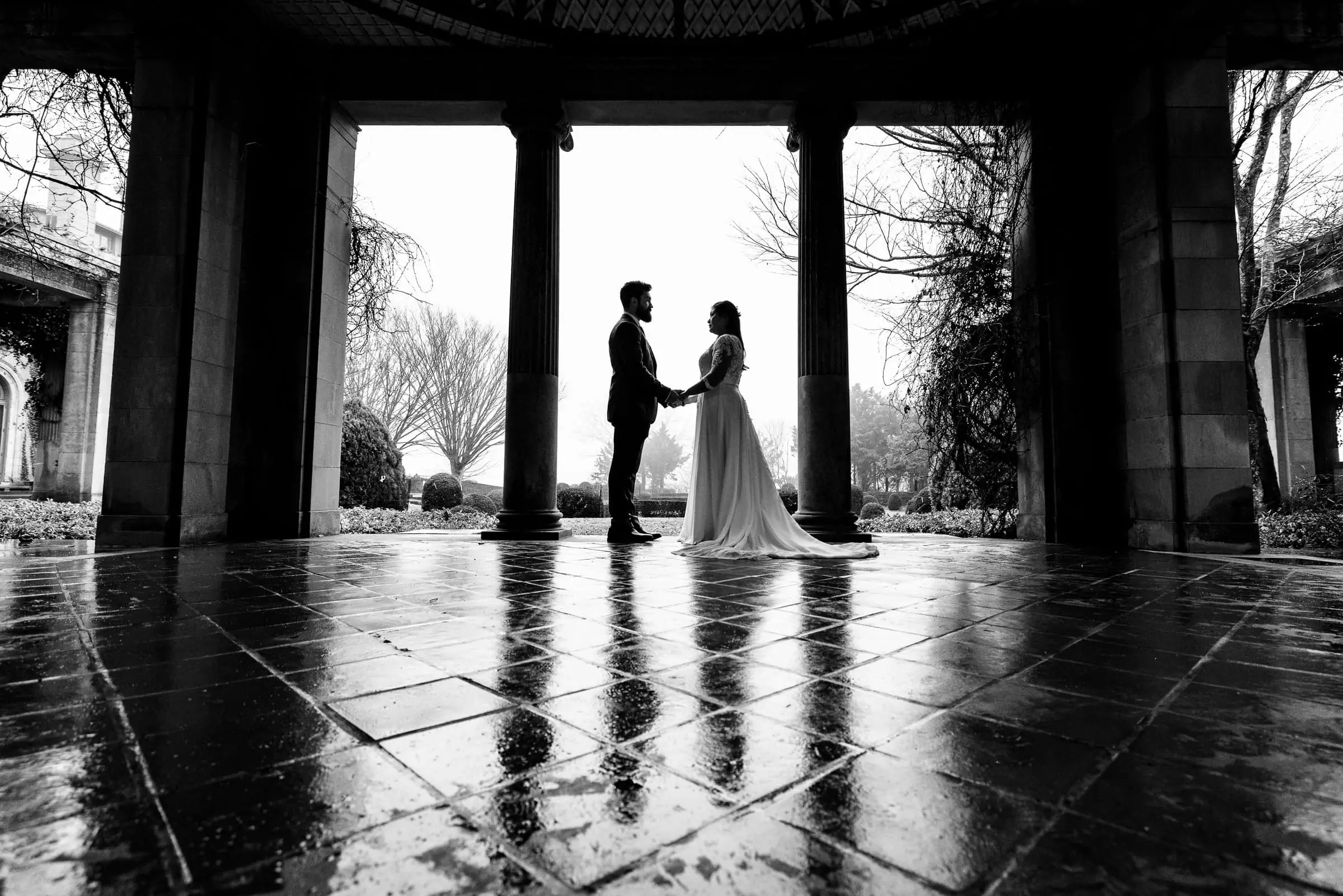 A man and woman in silhouette under a stone structure with a wet floor