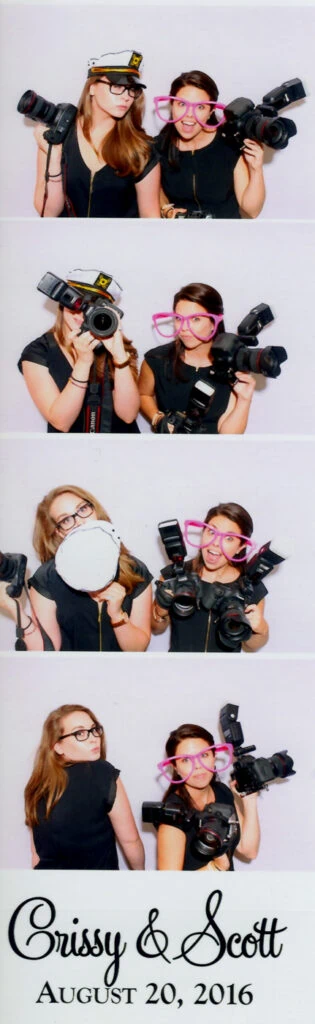 A photo booth film strip of four photos of two woman holding cameras