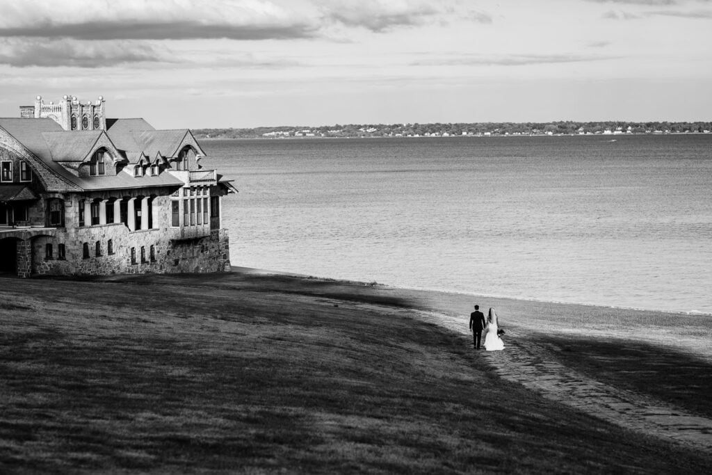 A bride and groom far away walking down a hill to the ocean