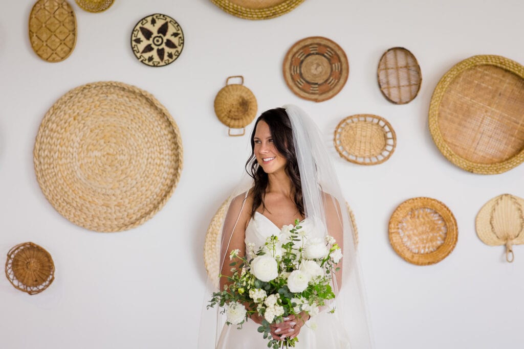 A bride poses for a wedding portrait in front of the basket wall in the Oyster Lounge at Newport Beach House