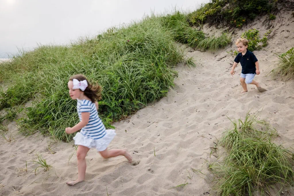 Two children running down a sand dune
