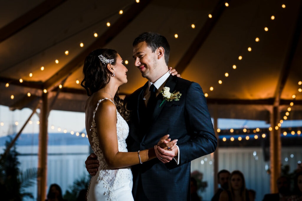 A bride and groom dancing under the lights in the tent at The Bohlin Weddings and Events