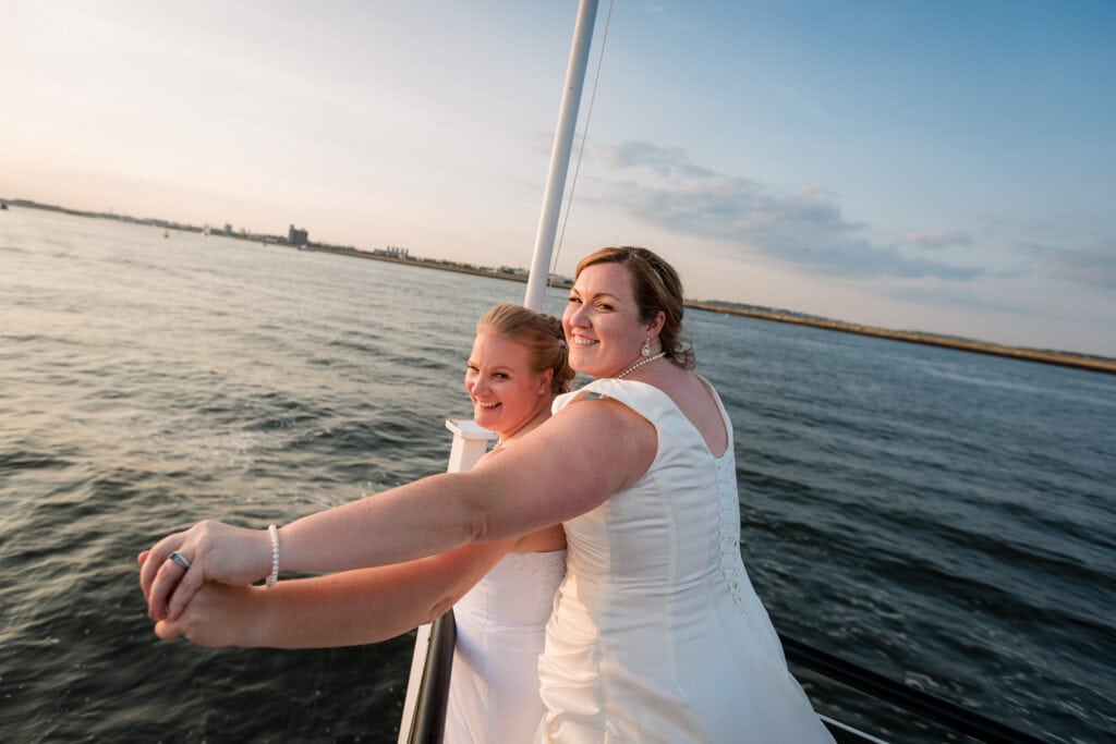 Two brides leaning out over the bow of a boat