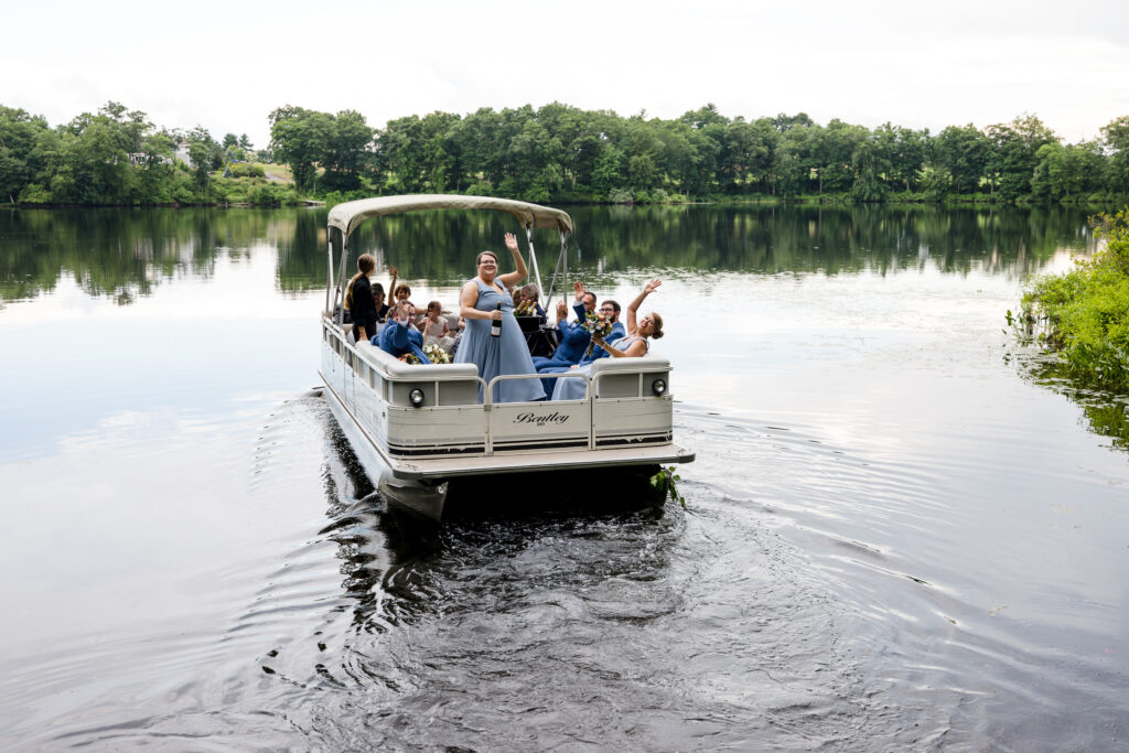 A wedding party waves as they leave on a pontoon boat